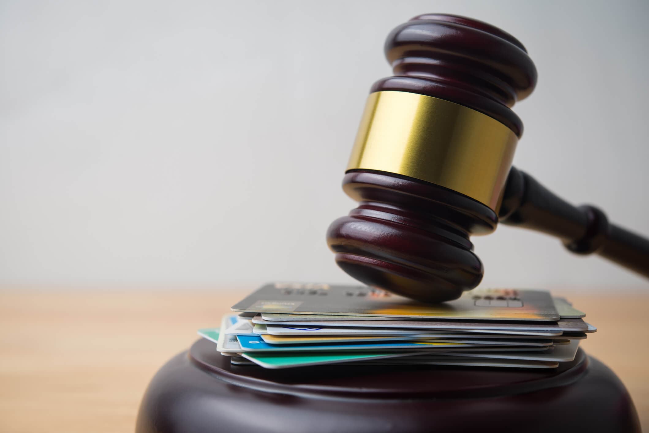 Judge’s gavel resting on credit cards, representing credit card companies suing consumers over unpaid debt.