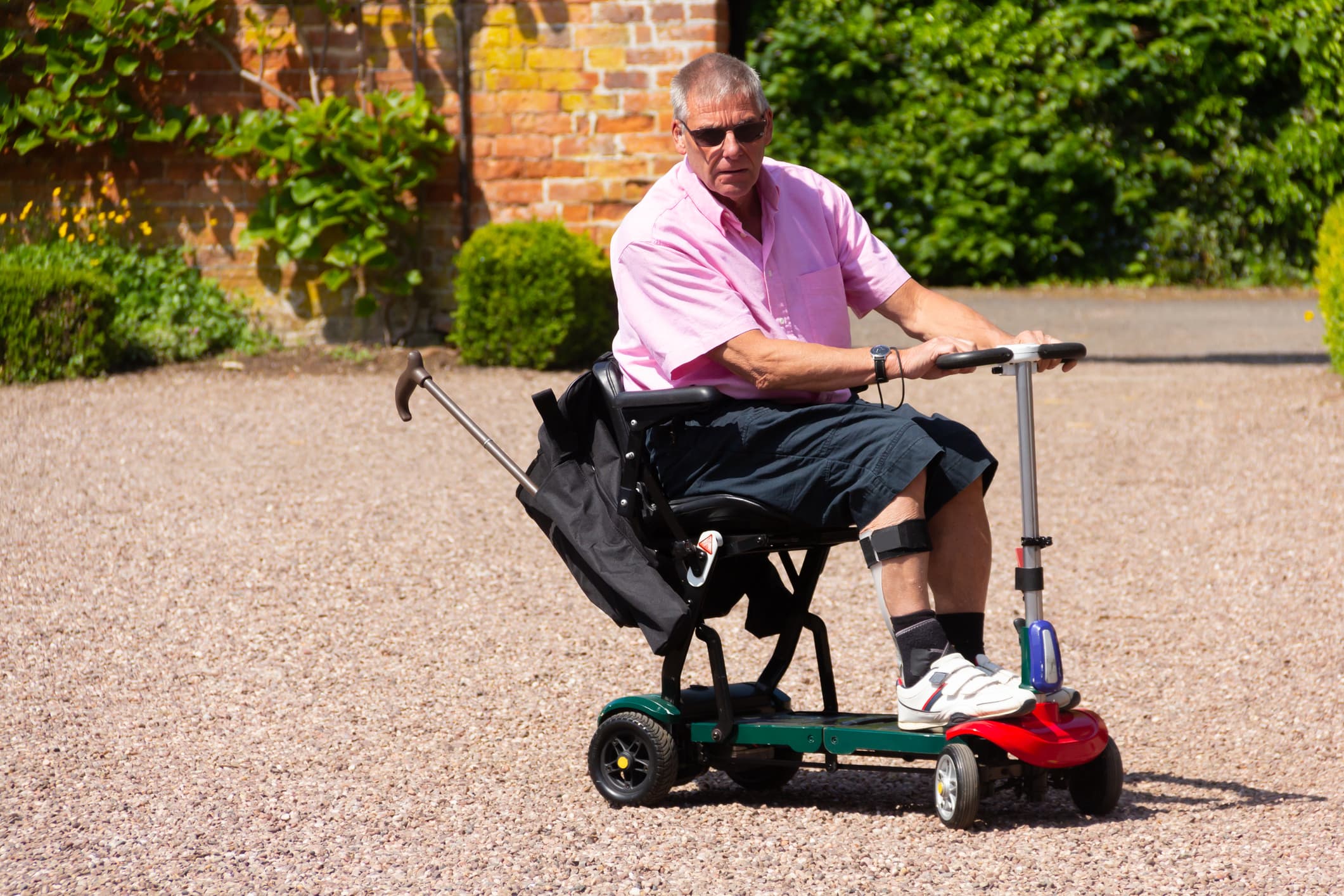 Senior riding a folding mobility scooter outdoors demonstrating portable mobility and easy transport