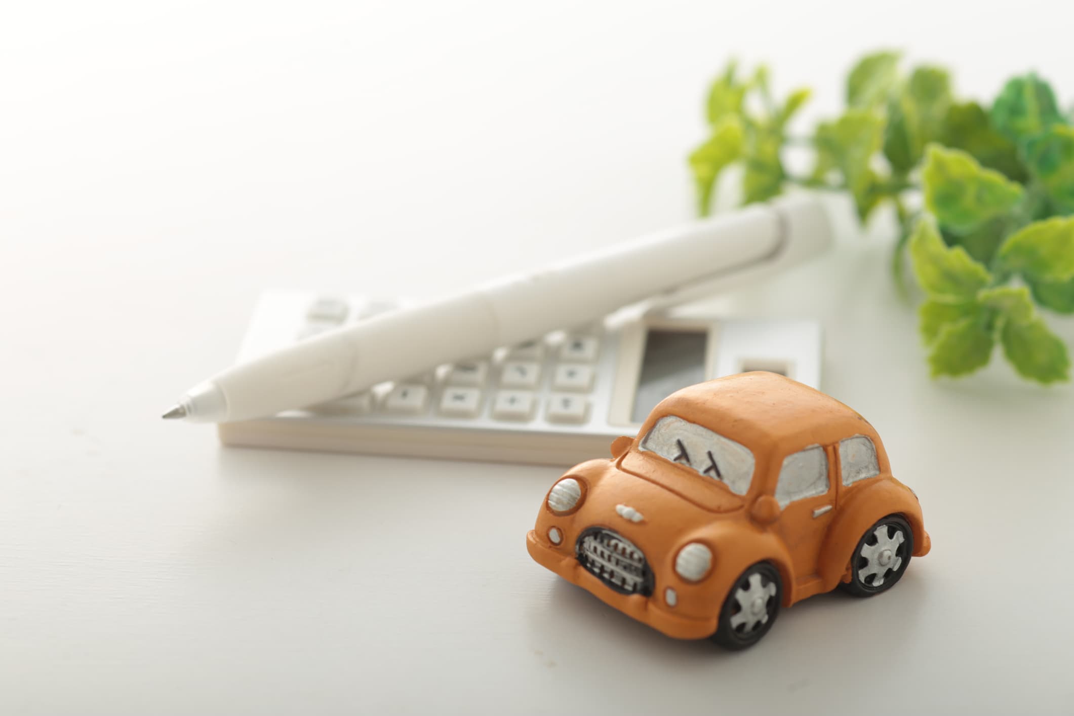 Orange toy car placed next to a calculator and pen, representing Upgrade auto loan refinancing