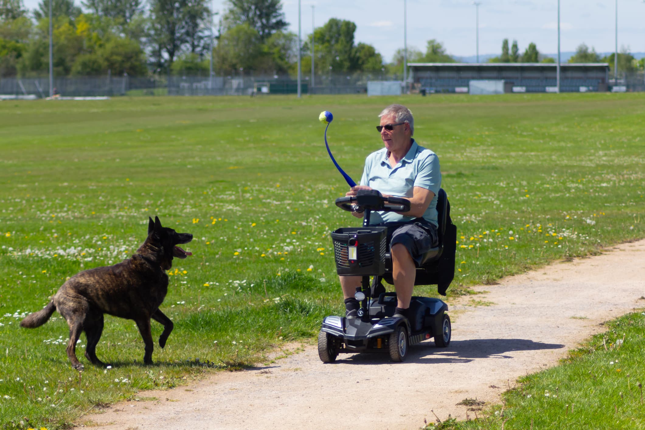 Senior using one of the best mobility scooters outdoors while playing with a dog in a park setting