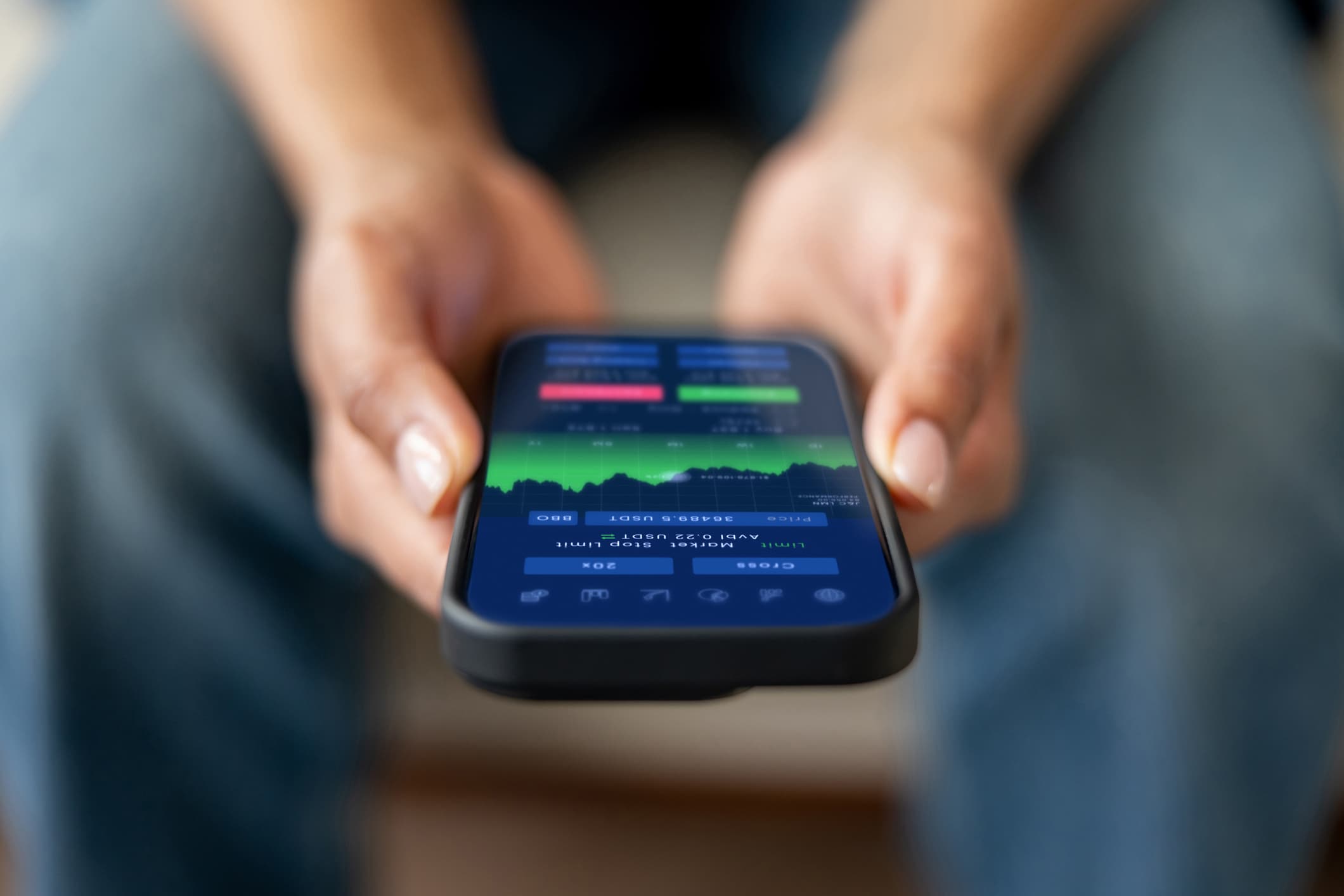 Hands holding a smartphone with a financial dashboard on screen, representing the best budgeting apps for managing money.