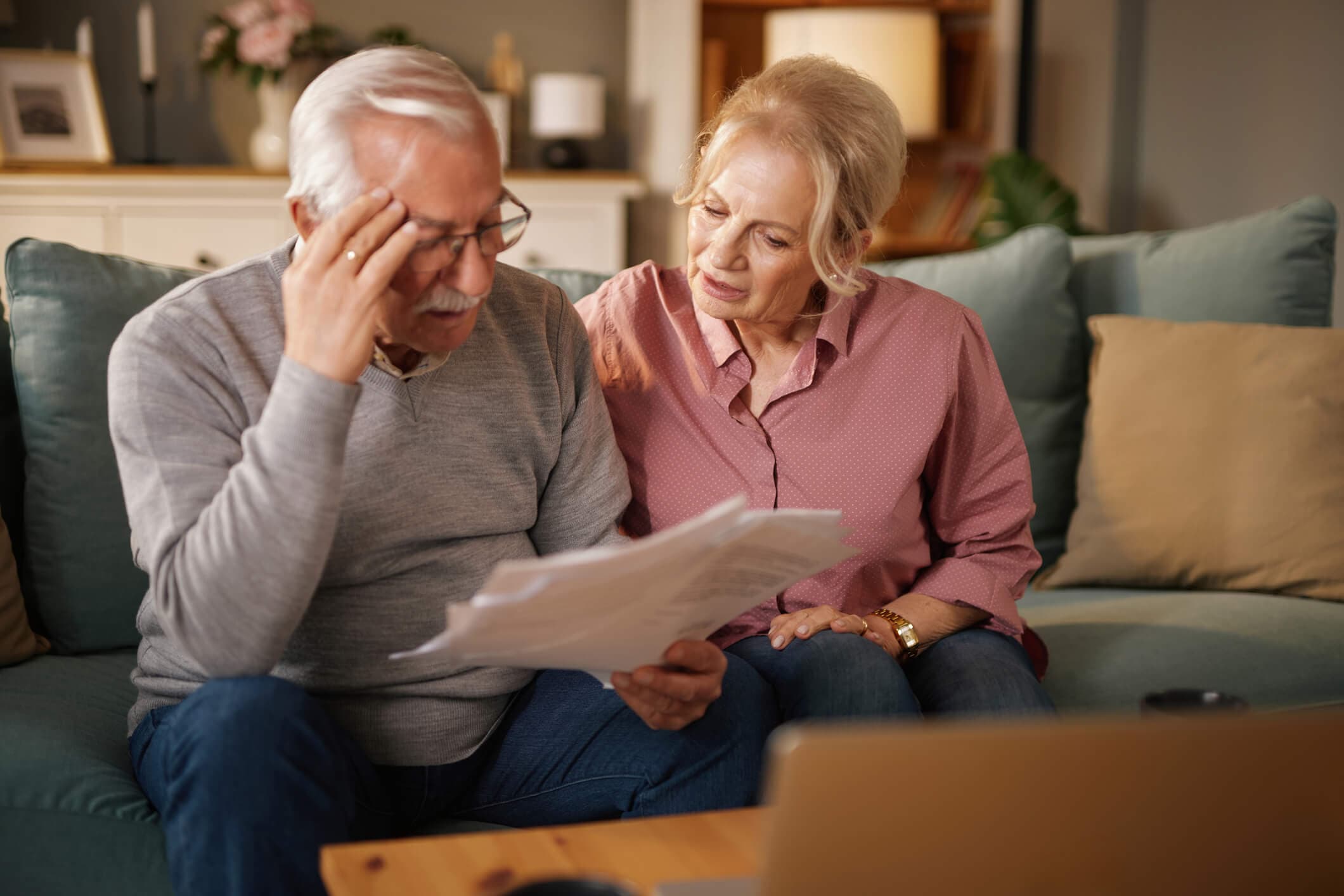 An older couple reviews bills and paperwork together at home. The image represents the financial stress of unpaid medical bills and the importance of reviewing charges, contacting healthcare providers, and exploring payment or financial assistance options.