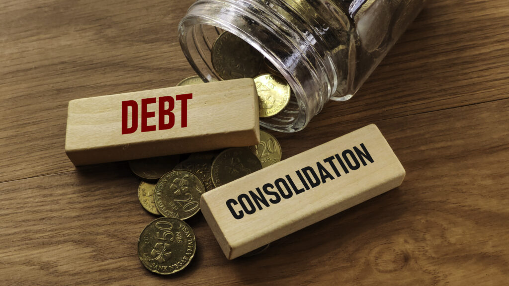 Wooden blocks labeled &ldquo;Debt&rdquo; and &ldquo;Consolidation&rdquo; with coins spilling from a jar, symbolizing Upgrade debt consolidation.