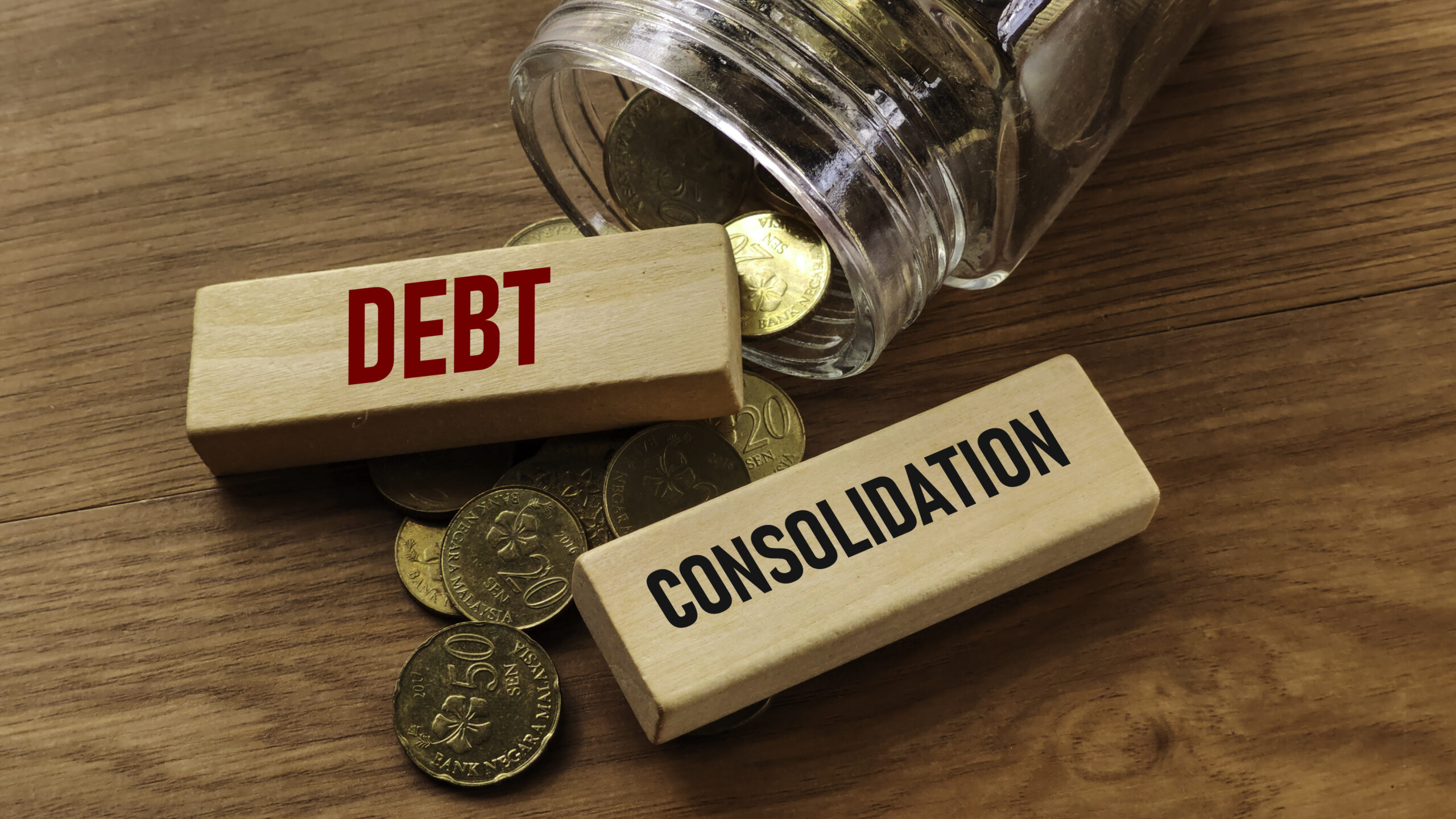Wooden blocks labeled “Debt” and “Consolidation” with coins spilling from a jar, symbolizing Upgrade debt consolidation.
