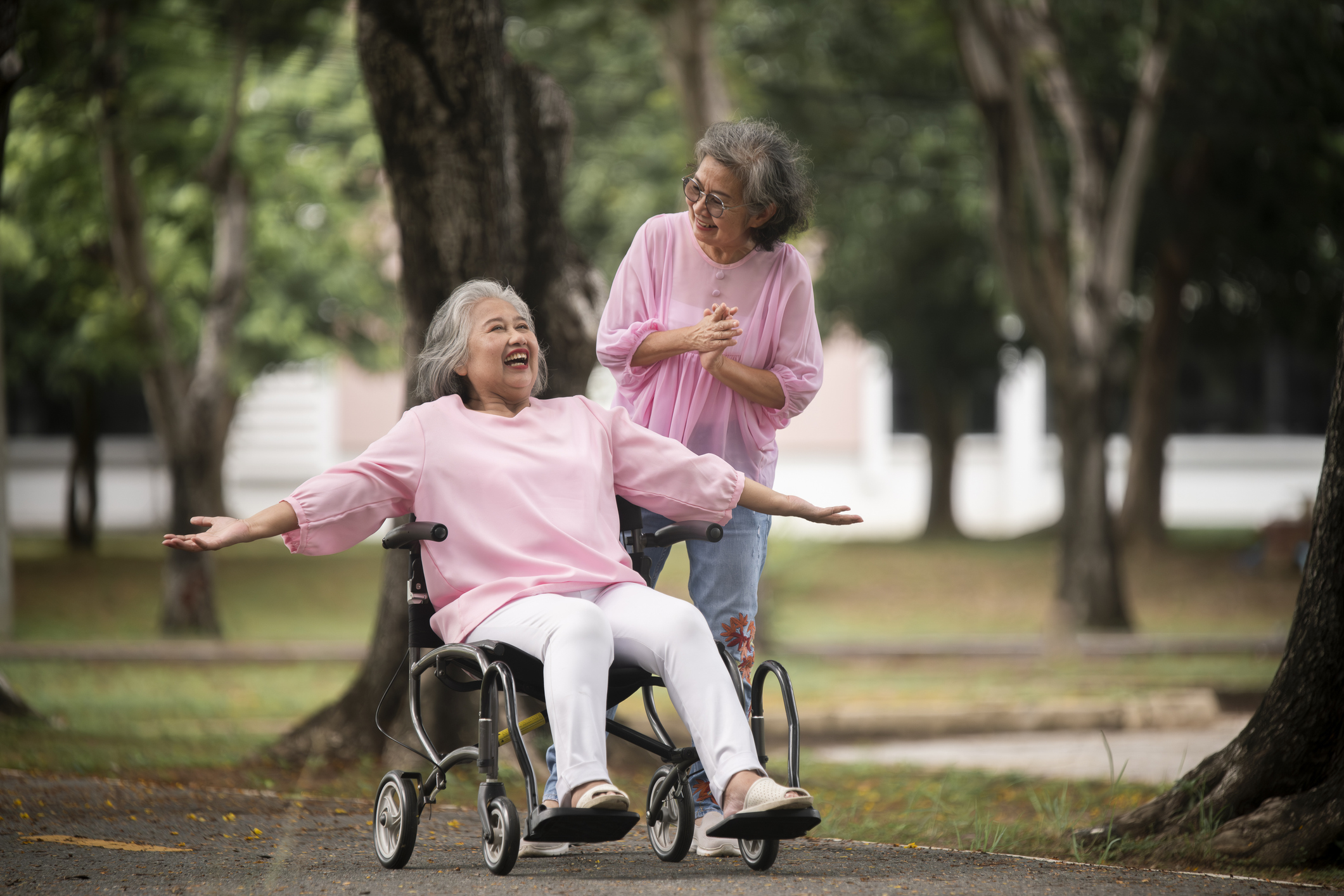 Two senior women enjoying time outdoors, with one using a wheelchair as a mobility aid—highlighting the benefits of mobility aids for seniors.