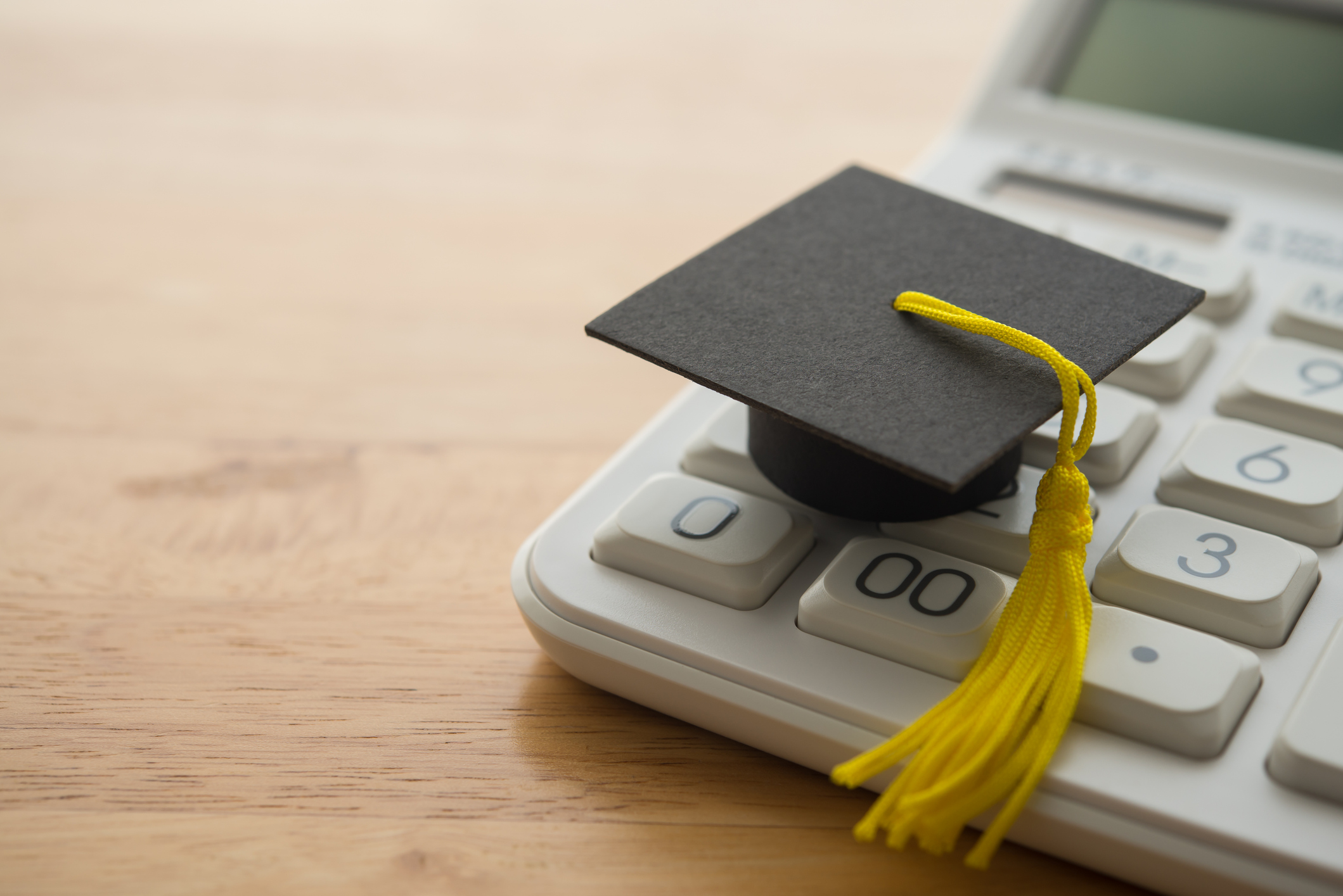 Graduation cap on calculator representing student loan refinance calculator and financial planning