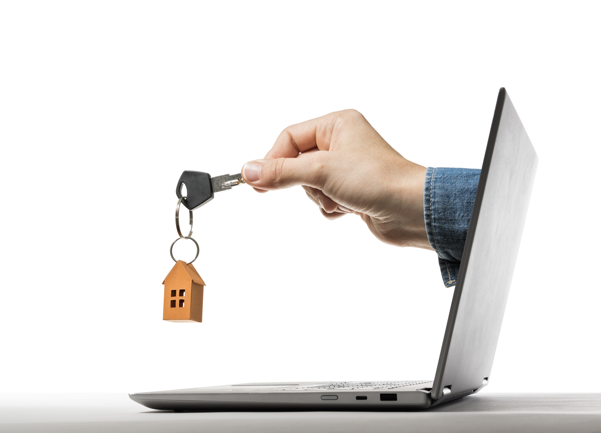 A hand holding a house key through a laptop screen, symbolizing online home loan services – perfect for illustrating LendingTree mortgage reviews.