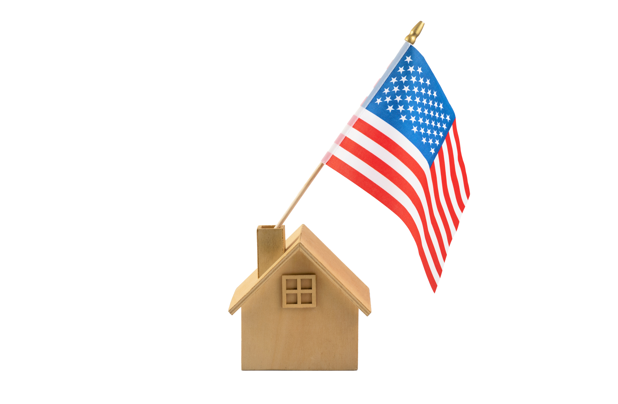 Small wooden house model with an American flag symbolizes patriotic homeownership—ideal for a Veterans United Home Loans reviews article.
