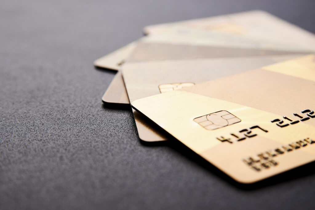 Several gold-colored credit cards stacked on a black surface, representing a balance transfer credit card for average credit.