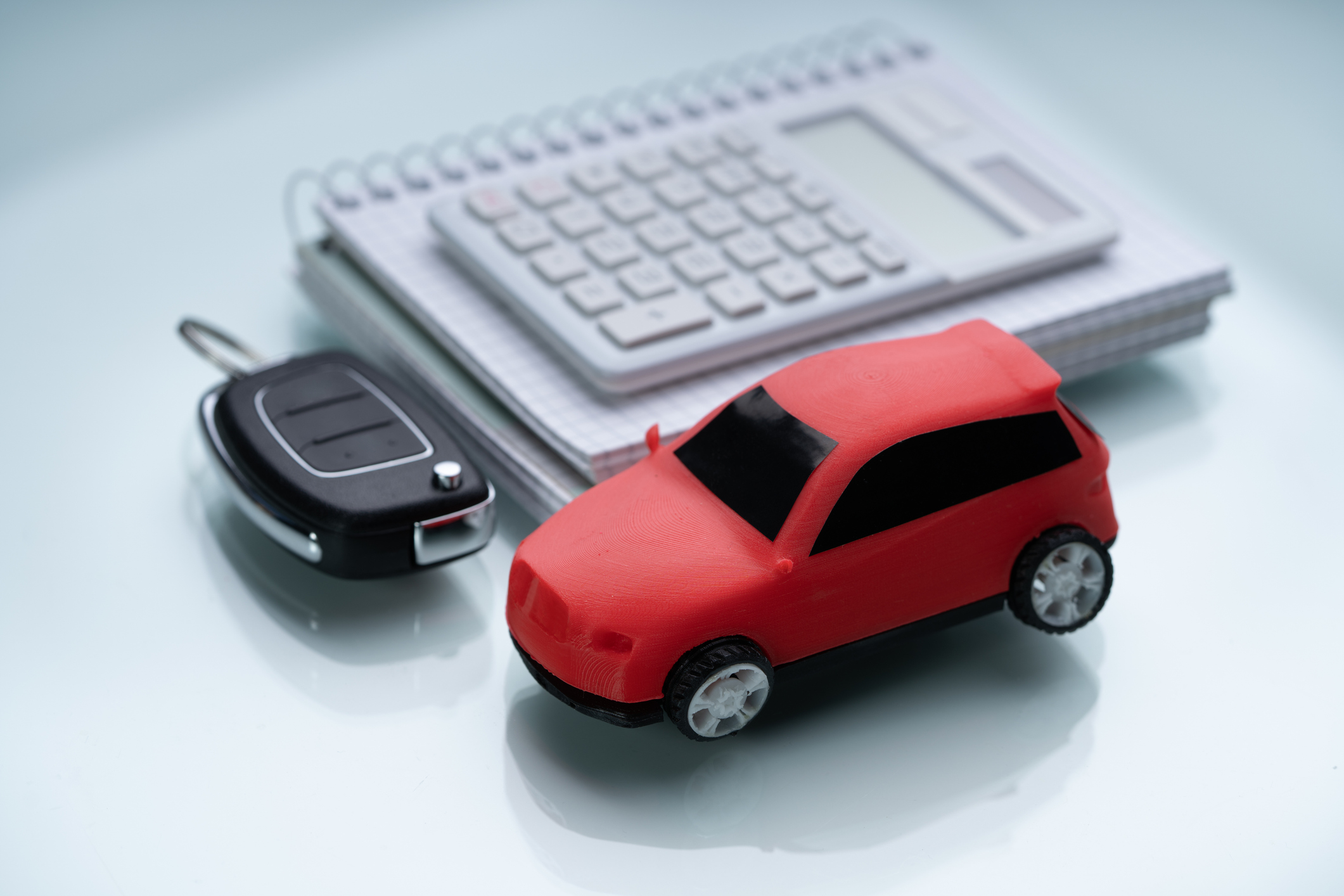 PenFed Auto Loan review concept with red toy car, key fob, and calculator on a desk, symbolizing car loan planning
