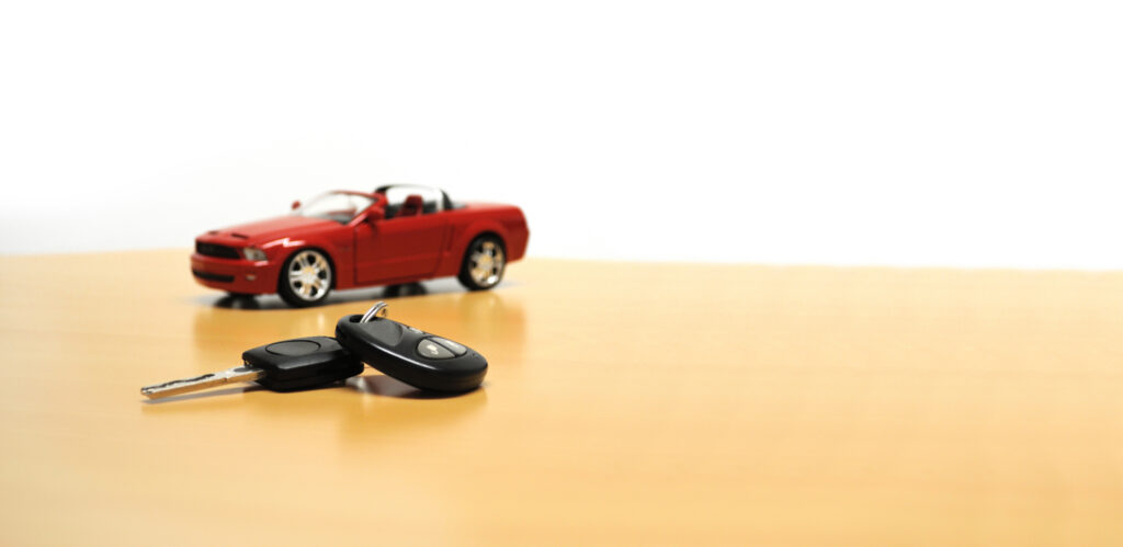 Car keys with a red convertible in the background symbolizing used auto loans.