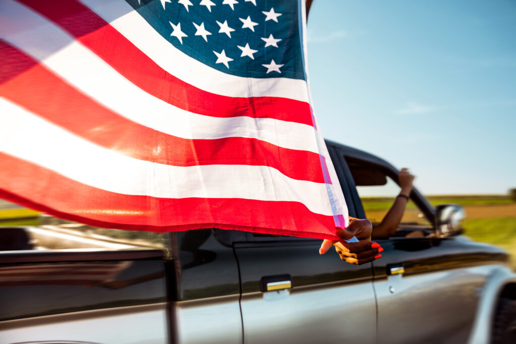 Driver holding an American flag from a truck window symbolizing Navy Federal Credit Union auto loan refinance for military borrowers.