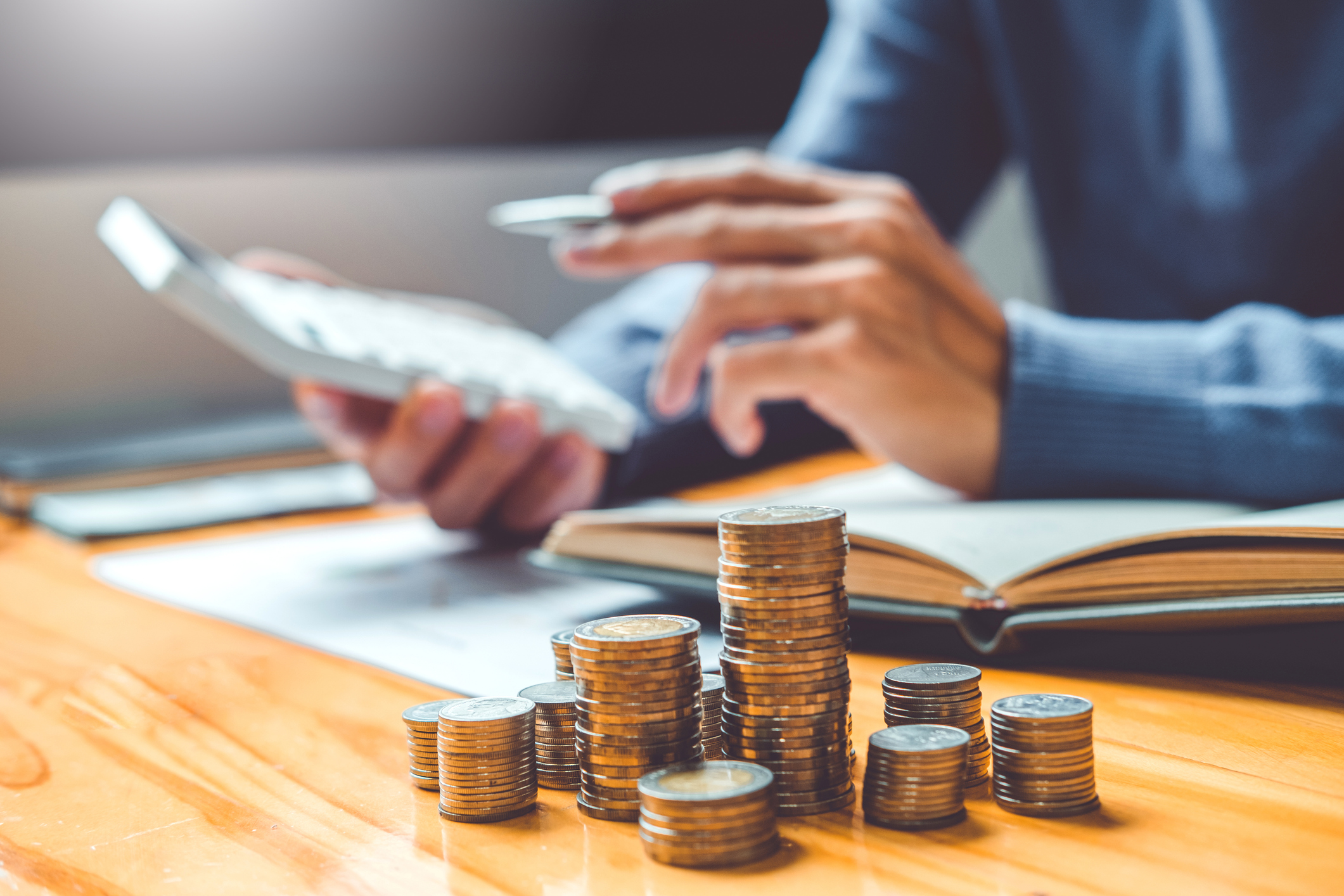 Person using a savings interest rate calculator to estimate compound interest growth with stacked coins on a desk