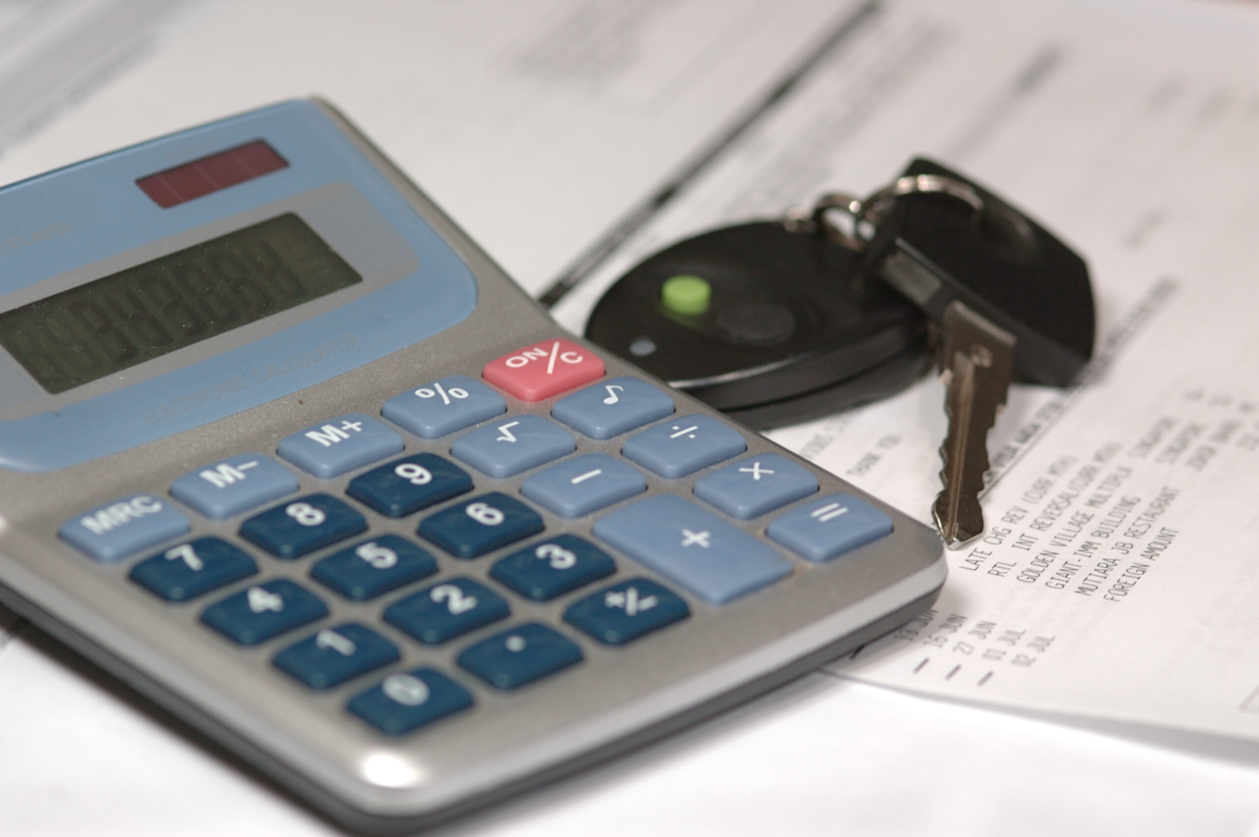 Auto loan early payoff calculator concept showing a calculator and car keys used to estimate savings from paying off a car loan early.