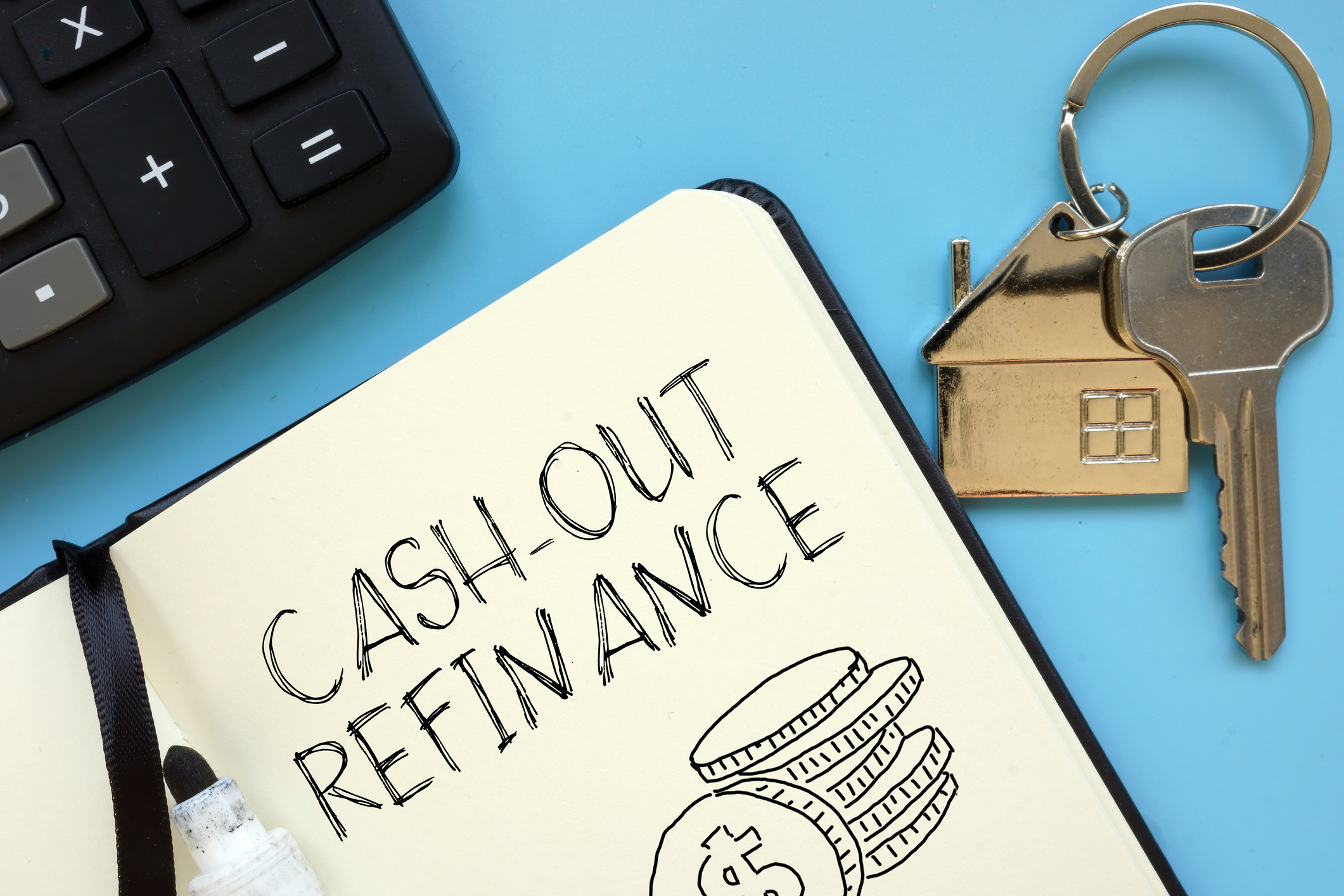 Top-down view of a notepad with "Cash-out Refinance" handwritten on the page, positioned next to a calculator and house keys to illustrate a cash-out mortgage refinance calculator.