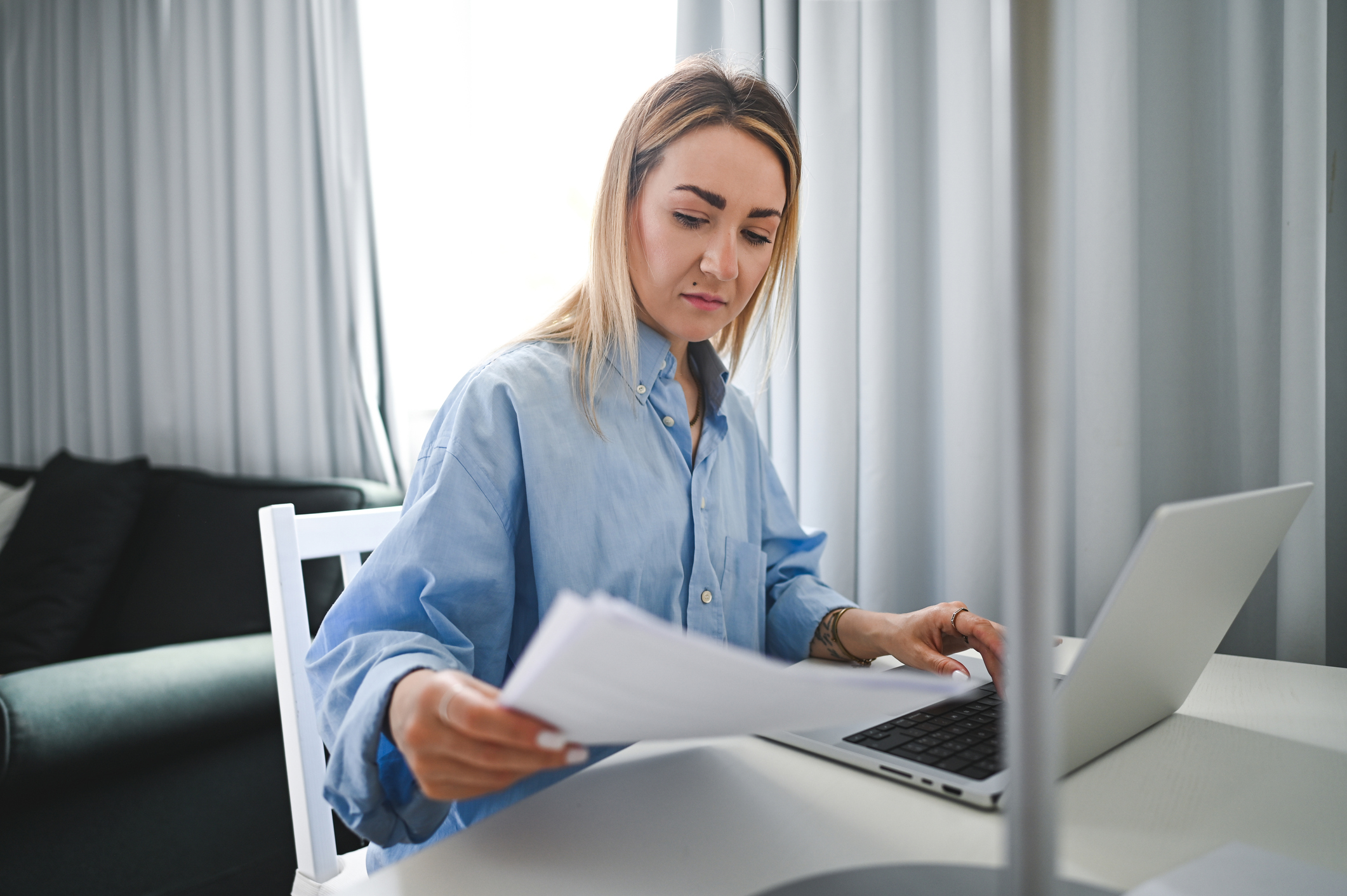 Woman reviewing loan documents on a laptop while deciding when to refinance