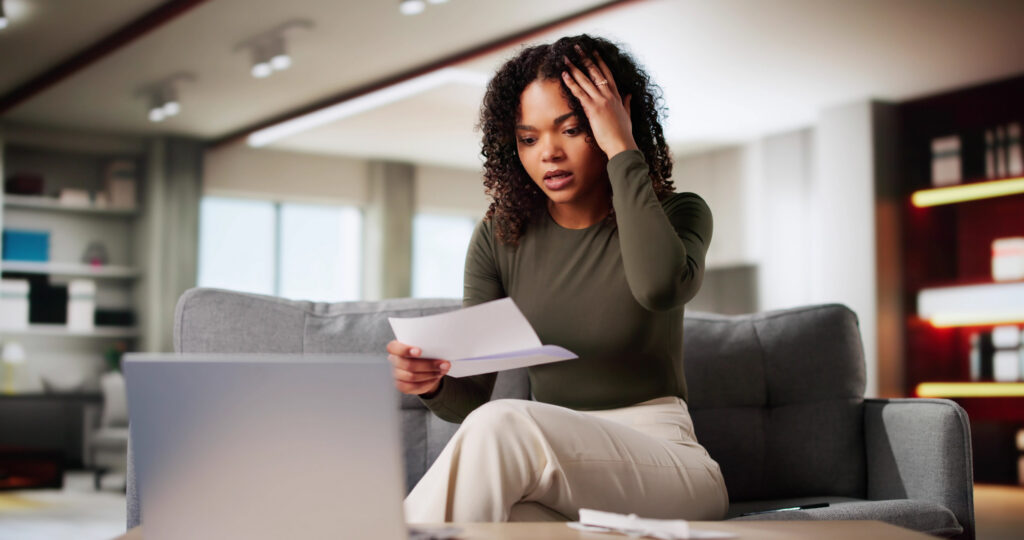 Woman looking stressed while reviewing bills at home because she can&rsquo;t pay credit card debt