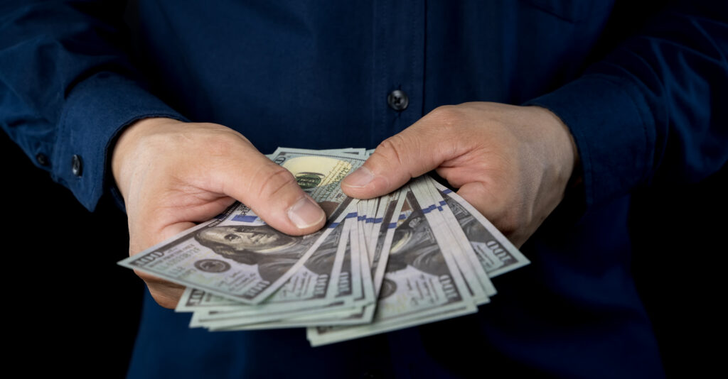 Hands holding cash representing how to spend your tax refund and make smart financial decisions