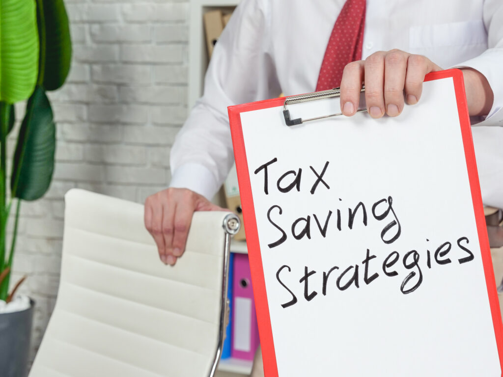 Professional holding a clipboard labeled tax saving strategies to help reduce income tax