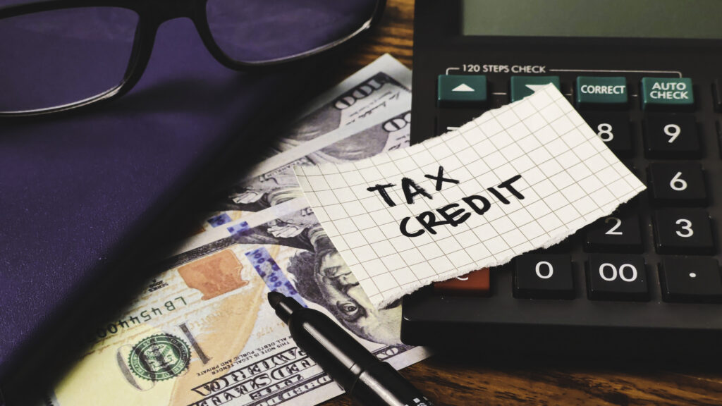 Calculator and money illustrating what is the savers credit and how it reduces taxes