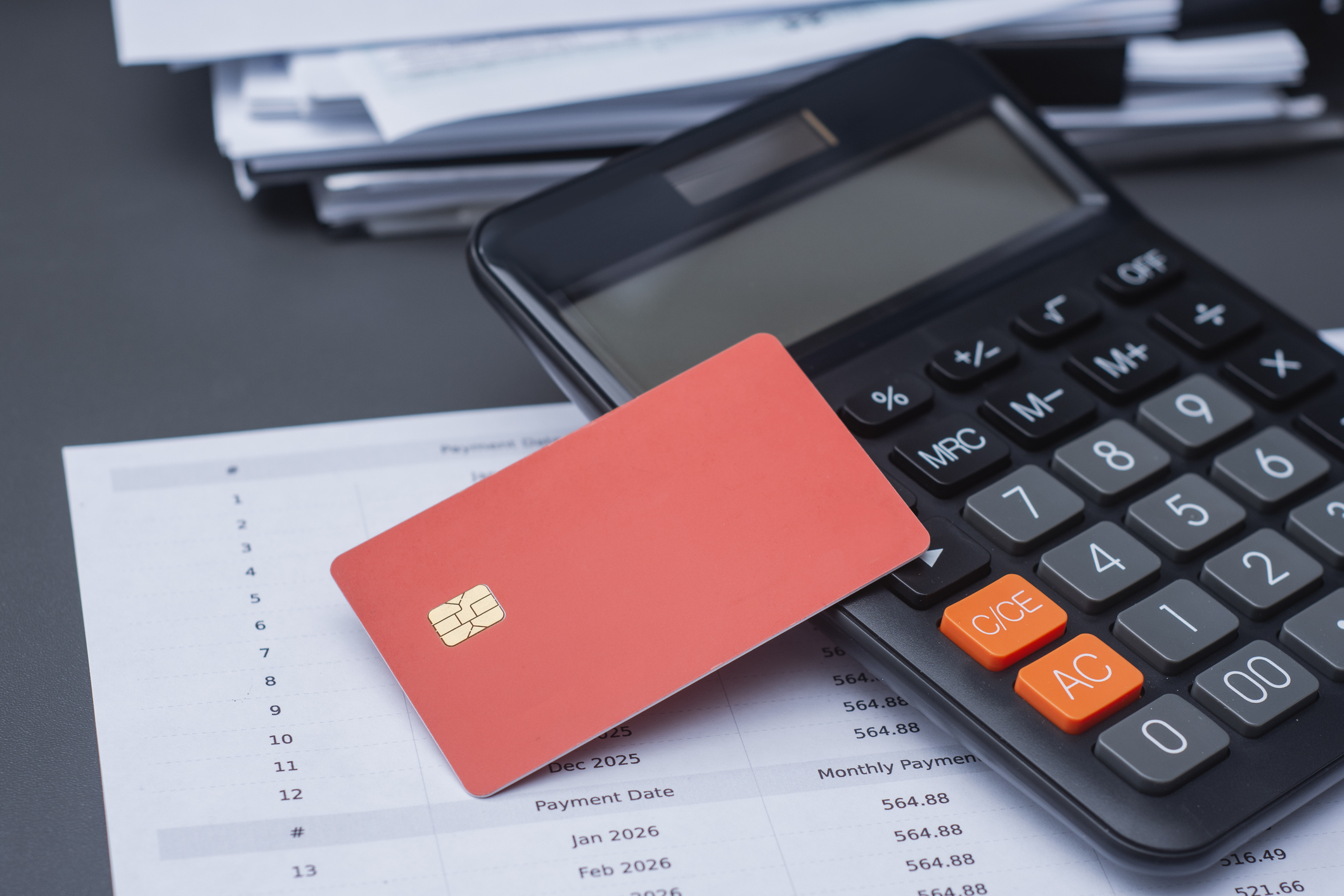 Credit card and calculator used to compare debt consolidation vs balance transfer costs